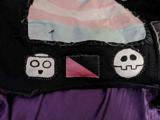 both the serv bot and bonne emblem patches on my jacket on each side of the queer anarchy flag