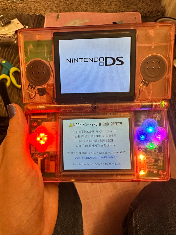 my clear pink ds lite showing rainbow leds under the buttons